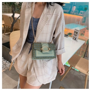 Detail of mint green tweed chain bag with oversized gold oval buckle on a blazer