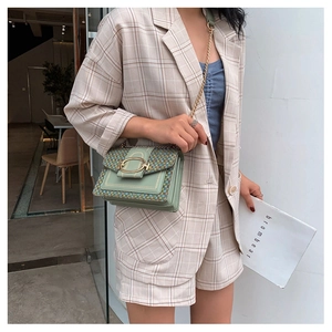 Detail view of sage green faux leather crossbody bag with woven tweed flap and gold chain