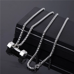 Silver dumbbell pendant necklace with box chain resting on a sleek black box display