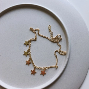 Detailed view of S925 sterling silver star anklet with gold finish on ceramic tray