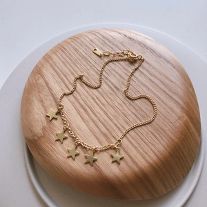 Minimalist 925 sterling silver anklet featuring five delicate gold star pendants on a wood tray