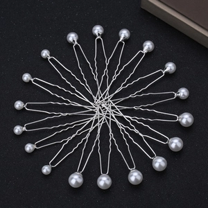 Radial arrangement of 18 silver U-shaped hair pins with white pearls on a black background