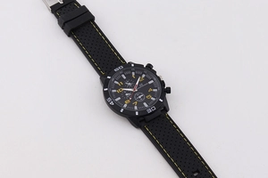 Detail view of black sports watch dial with yellow markers and silicone strap