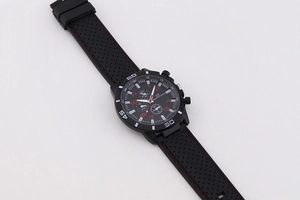 Detail of black sports chronograph watch with red stitching on perforated silicone strap