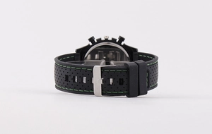 Detail of black silicone watch strap with green stitching and silver pin buckle closure