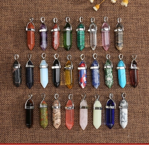 Detailed view of 24 assorted hexagonal crystal point pendants on brown textured fabric