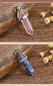 Macro detail of hexagonal pink and blue crystal column pendants on rustic wood