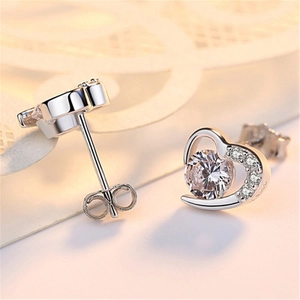 Macro detail of heart-shaped silver earrings with sparkling zircon claw setting