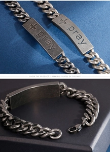 Detailed macro view of retro stainless steel curb chain bracelet with engraved pray cross plate