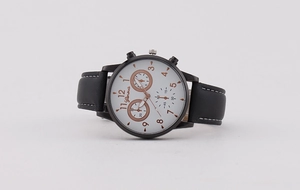 Detail of classic round white watch face with black leather strap and white stitching