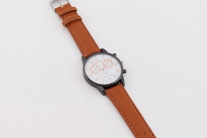 Macro detail of men's quartz watch with brown leather strap and three-eye dial