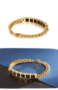 Macro detail of golden stainless steel abacus bracelet with black beads and chunky curb chain