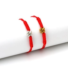 Detailed macro of red braided cord bracelets with gold and silver palm charms