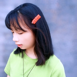 Close-up of vibrant orange gummy bear hair clips worn on black hair by a model