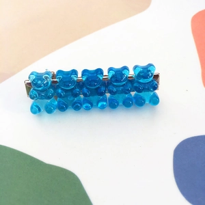 Detail of five translucent blue gummy bear resin charms on a silver metal hair clip