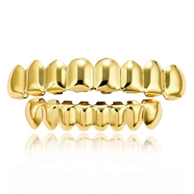 Close-up of hip-hop style gold teeth grillz set with clear reflection on white background