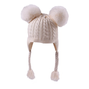 Detail view of cream knit baby hat with double pom poms and braided earflap ties