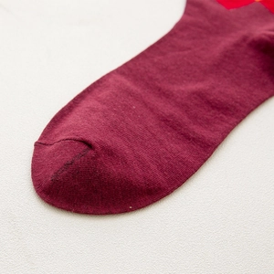 Close-up of fine stitching and knit texture on the toe of a burgundy diamond pattern sock