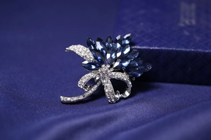 Detail view of deep blue crystal flower brooch with rhinestone bow on silk fabric