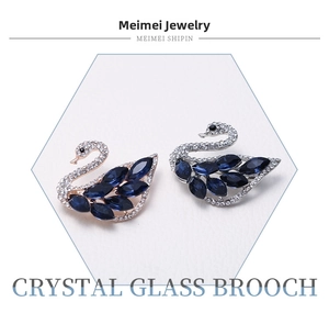 Detailed view of swan brooches with blue crystal glass in gold and silver settings