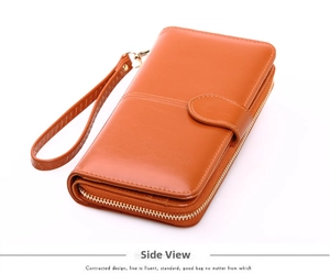 Side view of long orange faux leather wallet with wrist strap and zipper closure