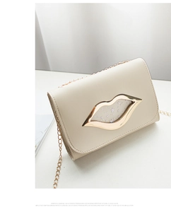 Detailed view of a cream crossbody bag with a distinctive golden lip-shaped ornament