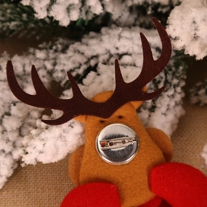 Handmade brown felt reindeer Christmas brooch with secure metal pin on festive background