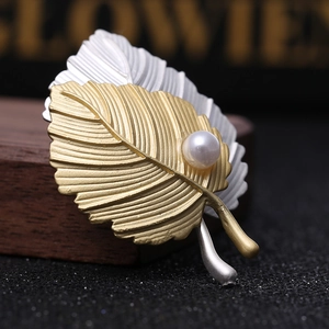 Matte leaf brooch in gold and silver finish with pearl detail and textured leaf veins