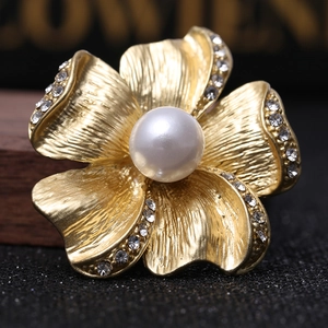 Matte gold flower brooch with central pearl and rhinestone accents on petals