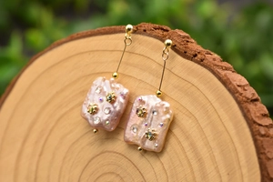 Detailed macro view of baroque pearl drop earrings with inlaid crystal flowers.