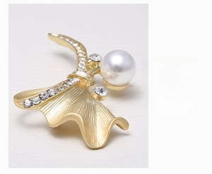 Macro shot of gold dragonfly brooch featuring white pearl and sparkling crystals detail