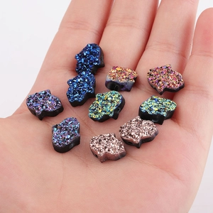 Perles Main de Fatima en résine colorée avec texture druzy présentées sur une main