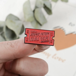 Macro shot of red enamel sci-fi movie ticket brooch held in hand with gift background