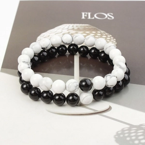 Detail of 8mm matte black and white turquoise beaded bracelets for couples on an art book
