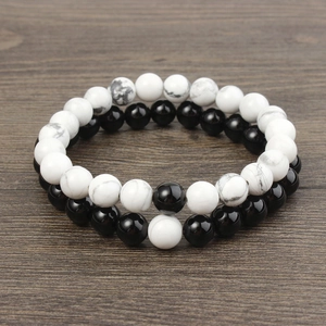 Detail of 8mm matte black and white turquoise beaded bracelets on a dark wood background