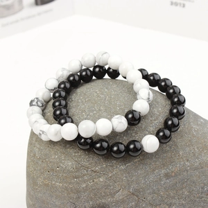 Close-up of 8mm matte black and white turquoise couple bracelets on a textured rock