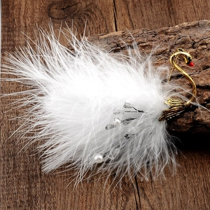 Detail of a gold swan brooch with fluffy white ostrich feathers and pearl accents on wood