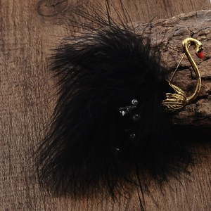 Elegant black swan brooch with fluffy feathers and gold finish on natural wood background