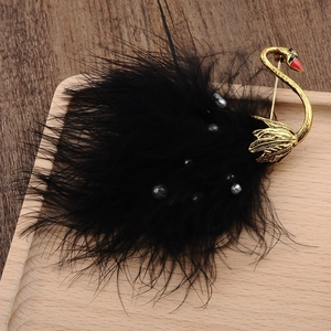 Detail of elegant black ostrich feather swan brooch with gold metal and red accents