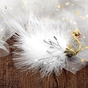 Close-up of golden swan brooch with fluffy white ostrich feathers and delicate pearls