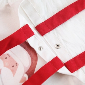 Close-up of canvas Christmas tote bag with red handle, metal snap button and Santa print