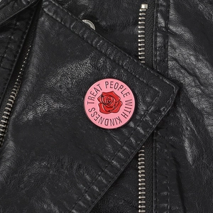 Pink enamel rose pin with 'TREAT PEOPLE WITH KINDNESS' text on black leather jacket