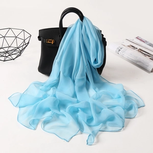 Elegant light blue silk scarf draped over a black handbag in a stylish studio setting