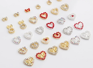 Close-up of heart and bunny ear nail art charms with red rhinestones and pearls