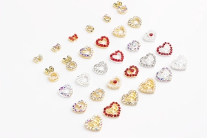Close-up of hollow heart and bow nail art charms with sparkling rhinestones and pearls