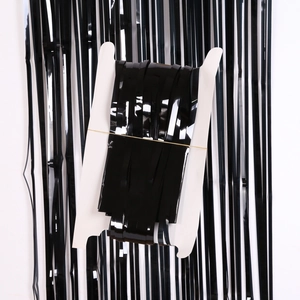 Detail of glossy black tinsel fringe curtain packaged on a white cardboard spool for party decoration