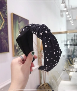 Detail of a black wide knotted headband featuring white pearls and sparkling rhinestones