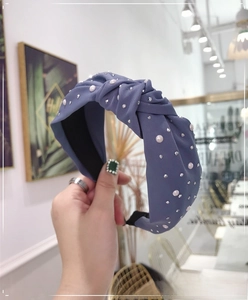 Detailed view of gray-blue knotted headband with rhinestones and faux pearls