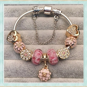 Macro shot of pink floral beads and crystal charms on a silver snake chain bracelet