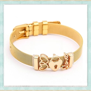 Macro detail of golden mesh bracelet featuring heart charms and a love pendant